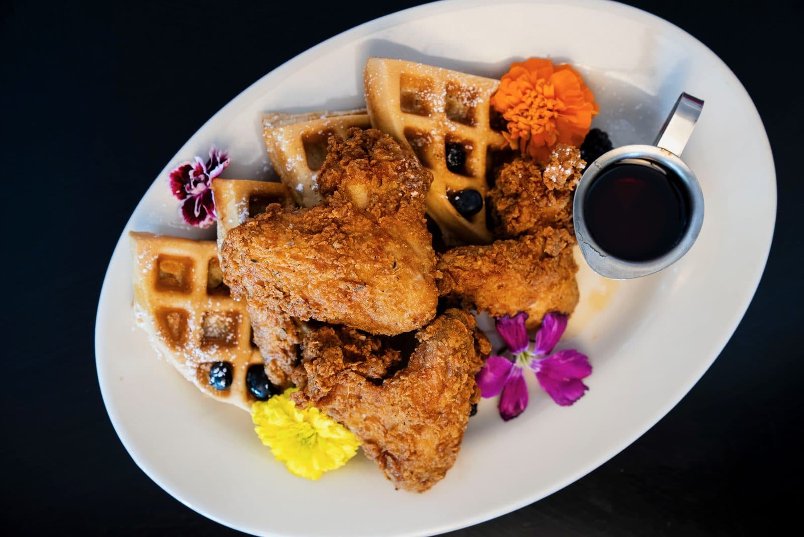 Chicken and waffles with syrup and edible flowers