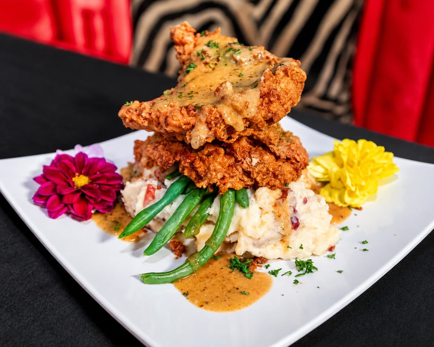 Fried chicken over mashed potatoes and green beans with gravy