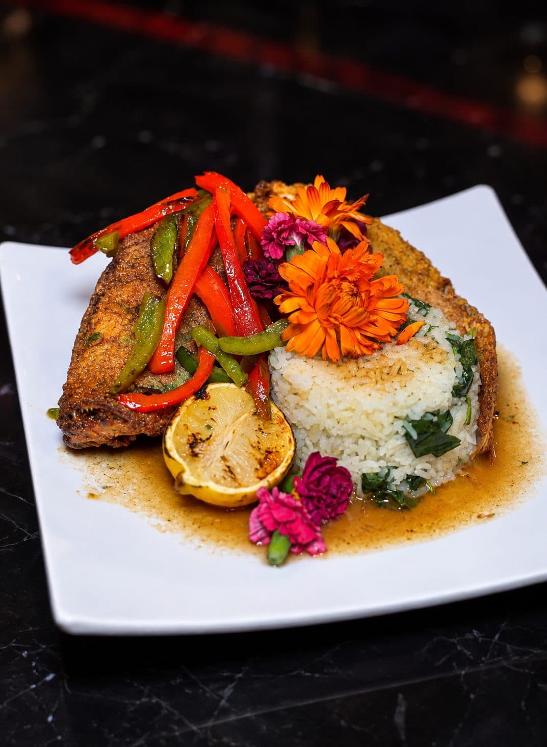 Whole fried fish with peppers over rice